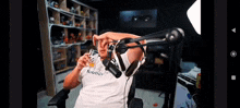 a man wearing headphones and a nautica shirt is sitting in front of a microphone