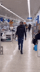 a man in a black vest and blue pants is walking through a store .