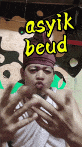 a man wearing a purple hat with the words asyik beud written above him