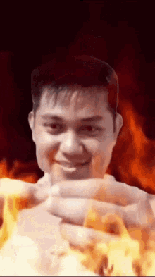 a man 's face is surrounded by flames while holding something in his hands