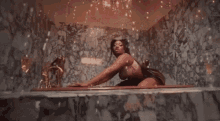 a woman is kneeling in a bathtub with her legs crossed .