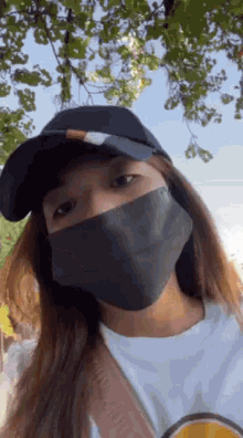 a woman wearing a hat and a mask is looking at the camera .