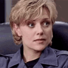 a woman in a police uniform is sitting in a chair and making a serious face .