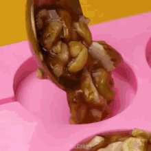 nuts are being poured into a pink container that says cakes