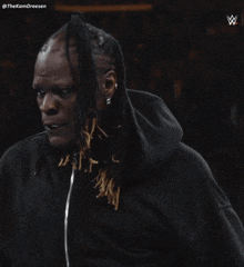 a man with dreadlocks is wearing a black hoodie with the letters w on the bottom