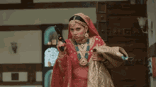 a bride in a red and gold dress holds a gun