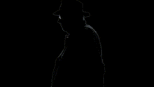 a silhouette of a man in a hat standing next to a skeleton