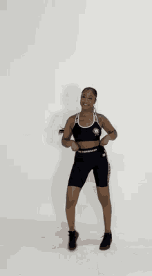 a woman wearing a black sports bra and shorts with the word converse on the side