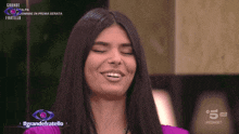 a woman is smiling in front of a sign that says grande fratello on it