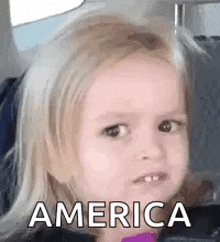 a little girl is sitting in a car seat and making a face .