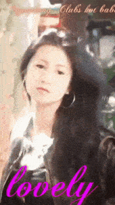 a woman with long black hair and hoop earrings is standing in front of a sign that says lovely