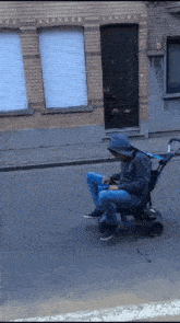 a man in a hoodie sits in a stroller on a street