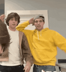 a man in a yellow hoodie stands next to another man