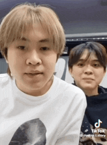 two young men are standing next to each other and one of them is wearing a tiktok shirt