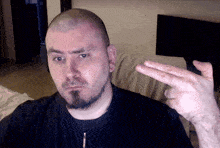 a man with a beard and a black shirt is making a peace sign