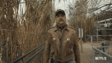 a man in a fringed leather jacket is standing in front of a netflix logo