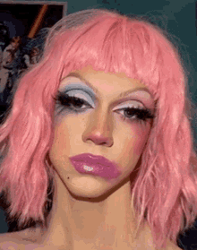a close up of a woman wearing a pink wig and blue and white makeup .