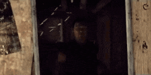 a man is looking out of a window in a dark room in a movie .