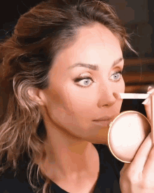 a close up of a woman applying makeup with a brush