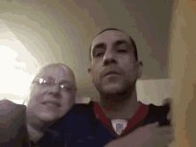 a man and a woman are posing for a picture together . the man is wearing a jersey with the word patriots on it .