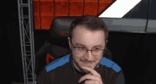a man wearing glasses and a black shirt is sitting in a res chair