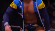 a man without a shirt is wearing a blue and yellow jacket