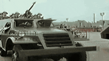 a black and white photo of a military vehicle driving down a road .