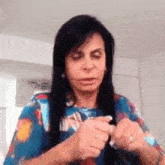a woman with long black hair is holding something in her hands and making a face .
