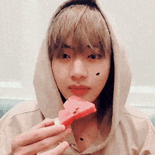 a person wearing a hoodie is eating a slice of watermelon