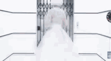 a woman in a white dress is walking down a hallway with a clock on the wall .