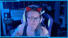 a woman wearing glasses and headphones is sitting in a chair in front of a computer screen .