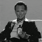 a man in a suit holds a bottle of atomic original
