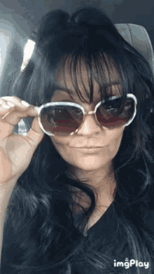 a woman is wearing sunglasses and making a funny face while sitting in a car