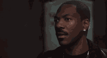 a man with a mustache and earrings is making a funny face in a dark room .