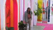a man in a suit is standing in a hallway with a pink carpet .