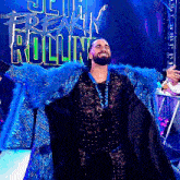 a wrestler in a blue and black outfit stands in front of a sign that says freak rolling