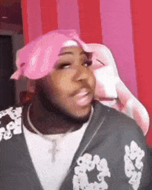 a man wearing a pink bandana and a black jacket is sitting in front of a pink chair .
