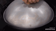 a person is putting a lid on a pan that says made in animatica