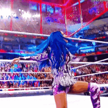 a woman with blue hair is standing in a wrestling ring .