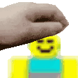 a hand is touching a yellow lego man 's face .