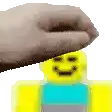 a hand is touching a yellow lego man 's face .