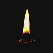 a candle with a yellow flame is lit up in the dark