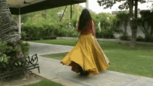 a woman in a long yellow skirt is dancing on a sidewalk