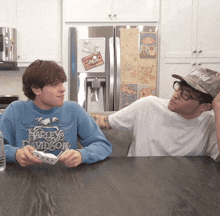 a man wearing a blue harley davidson sweatshirt sits at a table with another man