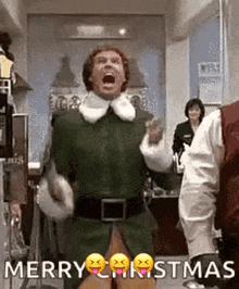 a man in a green elf costume is dancing in a room with the words `` merry christmas '' .