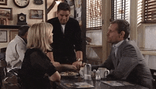 a man and a woman are sitting at a table in a restaurant talking to each other