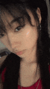 a close up of a woman taking a selfie with a red top and earrings .