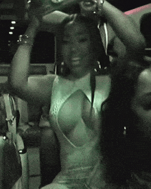 a woman in a white dress with a plunging neckline has her arms up in the air
