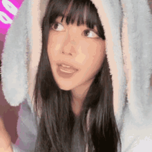 a close up of a woman wearing a bunny eared hoodie