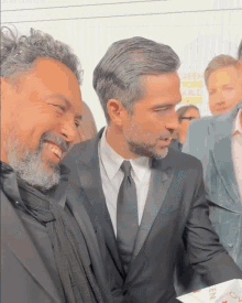 a man in a suit and tie is standing next to another man